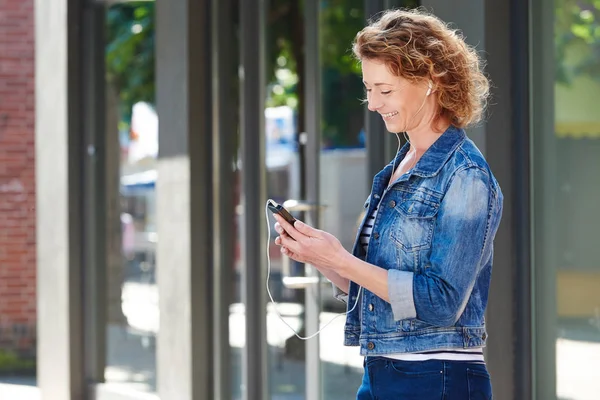 Kvinna i staden håller mobiltelefon — Stockfoto