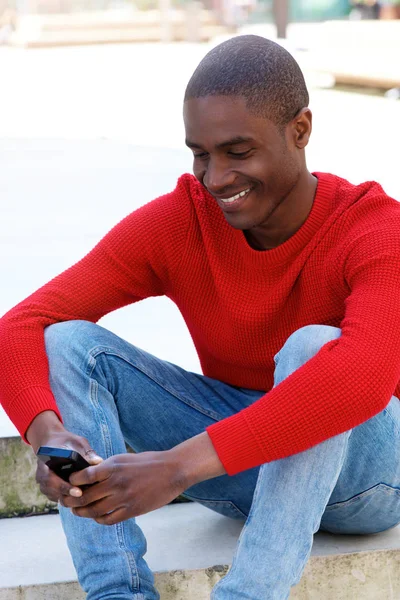 Mężczyzna siedzący na zewnątrz przy użyciu telefonu — Zdjęcie stockowe
