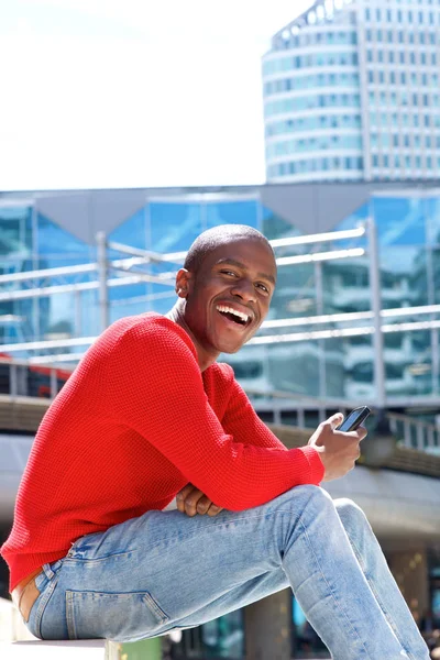 Hombre sentado fuera con teléfono celular — Foto de Stock