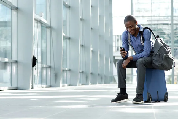 Businessman sitting with luggage and cellphone — Stock Photo, Image