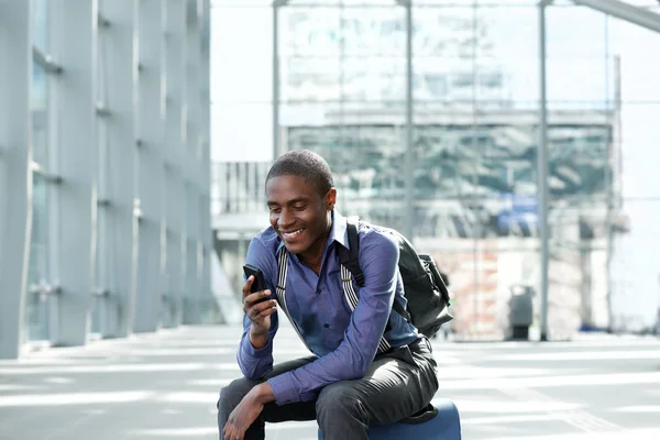 Affärsman som sitter med bagage och mobiltelefon — Stockfoto