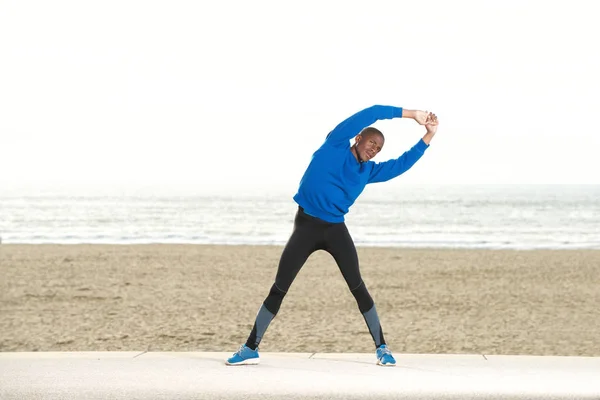 Man sträcker musklerna på stranden — Stockfoto