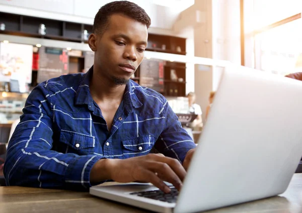 Homme assis dans un café travaillant sur un ordinateur portable — Photo