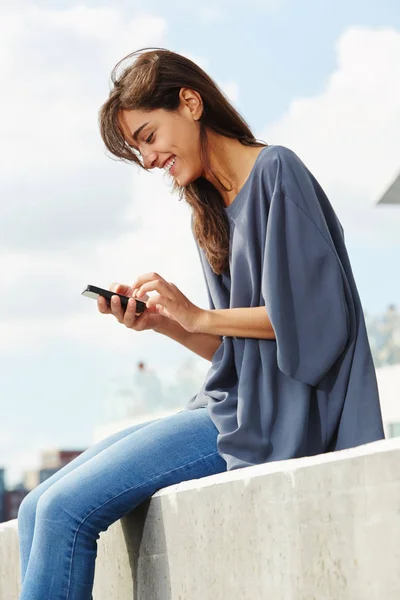 Vrouw zitten buiten met telefoon — Stockfoto