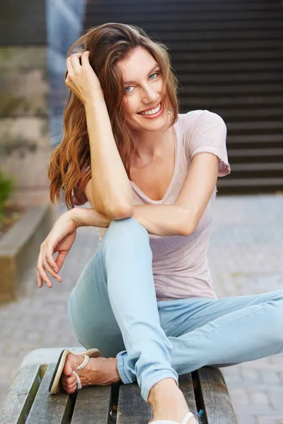 Vrouw zitten buiten en glimlachen — Stockfoto