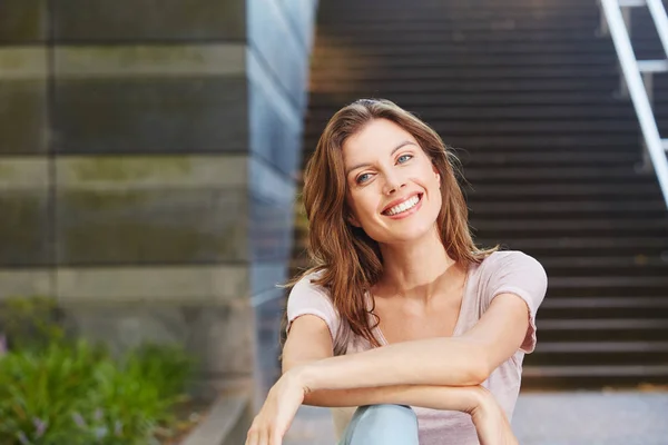 Vrouw zitten buiten en glimlachen — Stockfoto