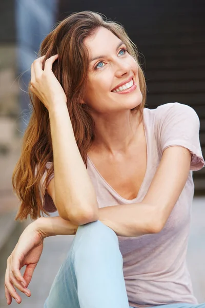 Mulher sentada ao ar livre e sorrindo — Fotografia de Stock