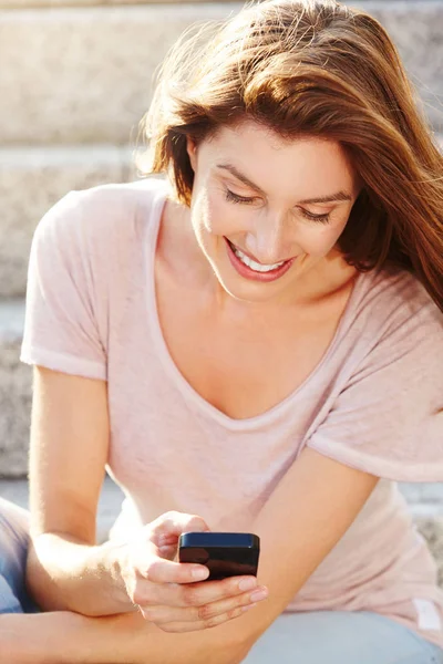 Woman sitting on steps with smart phone — Stock Photo, Image