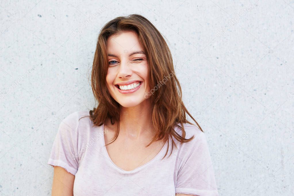 Young lady smiling against wall