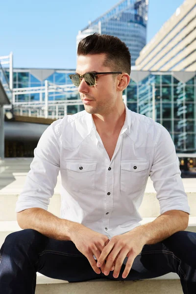 Man sitting in city with sunglasses — Stock Photo, Image