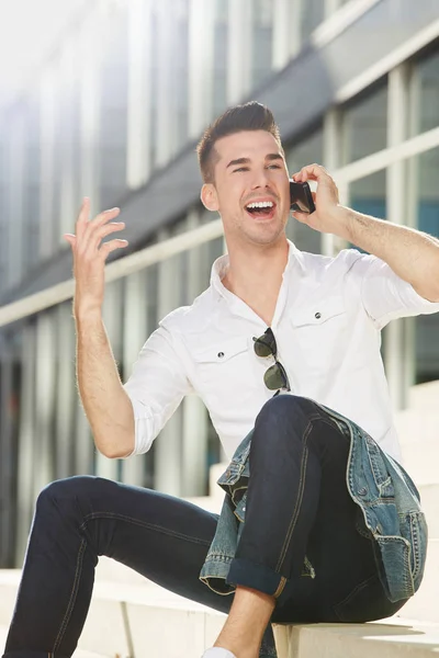 Homem ao telefone sentado no exterior da cidade — Fotografia de Stock