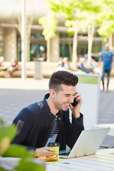 Man op telefoongesprek met laptop op café — Stockfoto