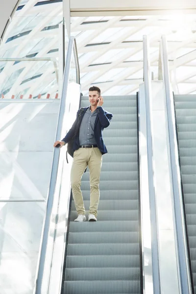 Hombre en llamada telefónica por escalera mecánica —  Fotos de Stock