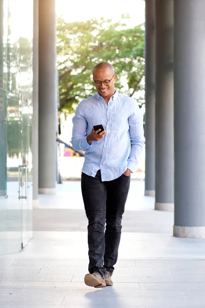 Afrikaanse man lopen met mobiele telefoon — Stockfoto