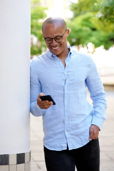 Zakenman leunend op muur met mobiele telefoon — Stockfoto