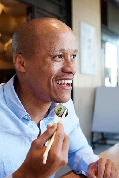 Afrikanska mannen leende njuta av sushi — Stockfoto