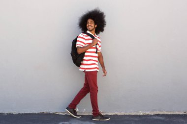 Duvar tarafından yürüyüş çanta ile öğrenci