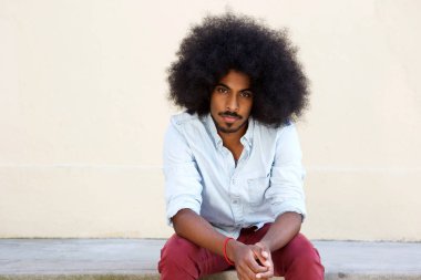 adam kaldırımda oturan afro saç modeli ile