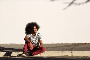 telefon ile kaldırımda oturan adam