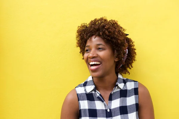 Женщина смеется над желтой стеной — стоковое фото