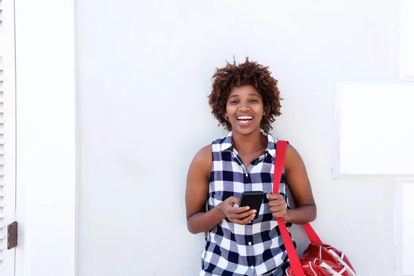 Kobieta, śmiejąc się z telefonu komórkowego i torba — Zdjęcie stockowe