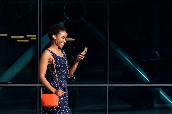 Vrouw lopen in de stad met mobiel en oortelefoons — Stockfoto