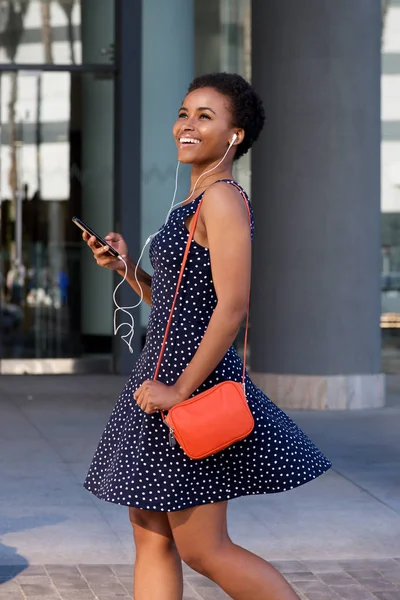 Kvinnan promenader i city med mobiltelefon och hörlurar — Stockfoto