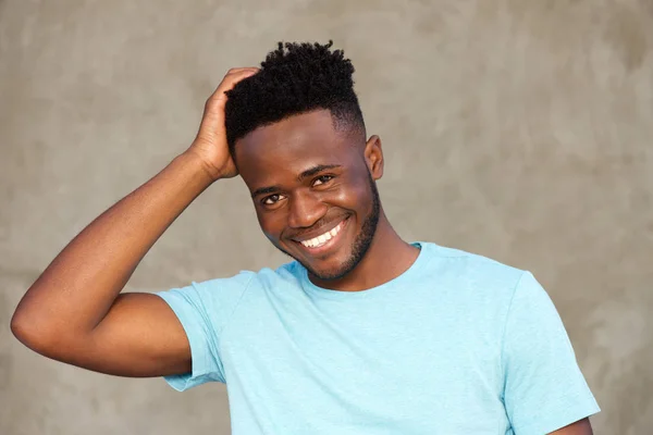 Homem sorrindo e de pé com a mão no cabelo — Fotografia de Stock