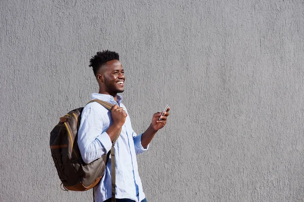 Hombre con bolsa y celular caminando por la pared —  Fotos de Stock