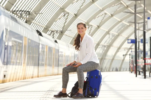 Femme assise sur une valise tenant un téléphone intelligent — Photo