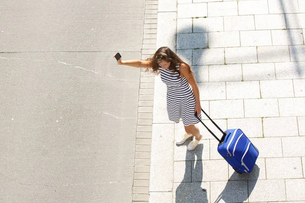 Kobieta, podnosząc rękę z telefonu komórkowego i walizka — Zdjęcie stockowe