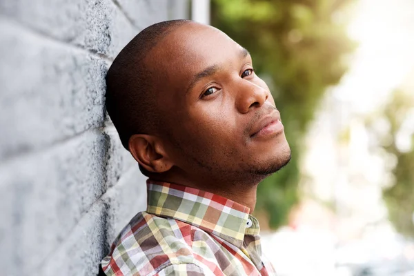 Young man leaning against wall and thinking — Stock Photo, Image