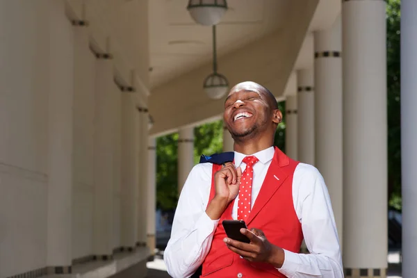 Afrykański mężczyzna w garniturze śmiejąc się z telefonem komórkowym — Zdjęcie stockowe