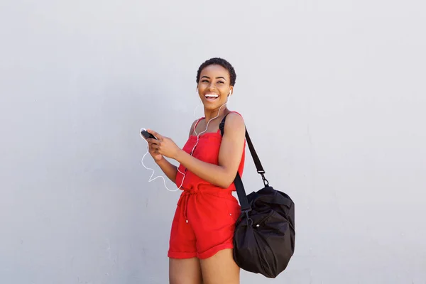 Mujer sonriendo con el teléfono celular y los auriculares — Foto de Stock