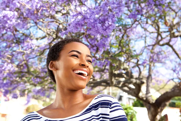 Woman laughing outdoors by flower tree — Stock Photo, Image