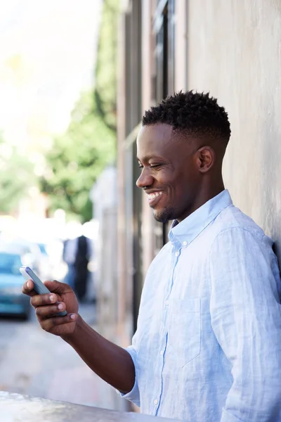 Человек стоит снаружи и смотрит на мобильный телефон — стоковое фото