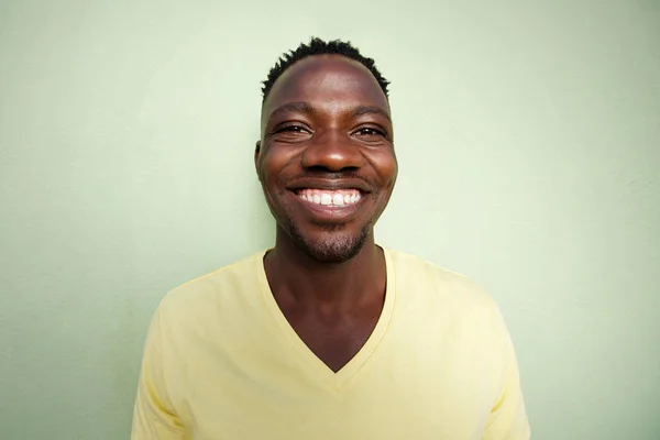 Uomo africano sorridente contro muro verde — Foto Stock