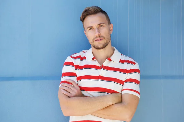 Man with arms crossed against blue wall — Stock Photo, Image