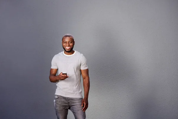 Hombre con teléfono inteligente de pie por la pared —  Fotos de Stock