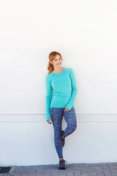 Sporty woman standing by wall — Stock Photo, Image