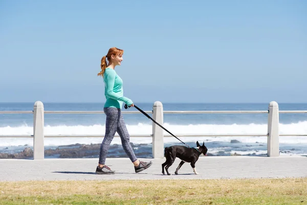 Woman walking with dog by sea — Stock Photo, Image