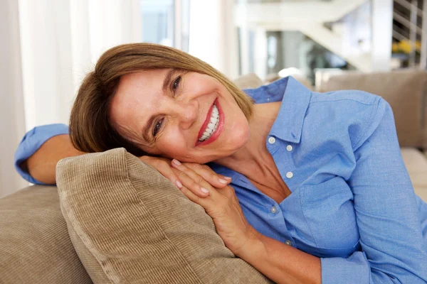 Evde kanepenin üzerinde gülümseyen kadın — Stok fotoğraf