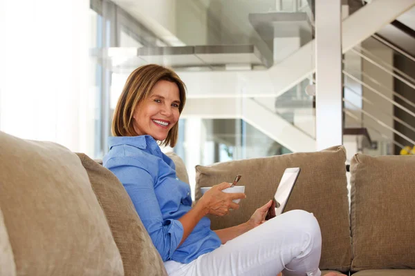 Woman sitting on sofa with bowl — Stock Photo, Image