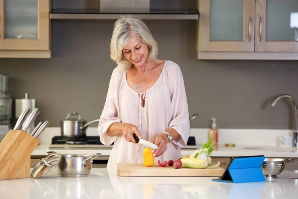 Older woman cutting vegetables — Stock Photo, Image