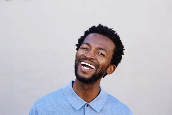 Hombre sonriendo por la pared blanca — Foto de Stock