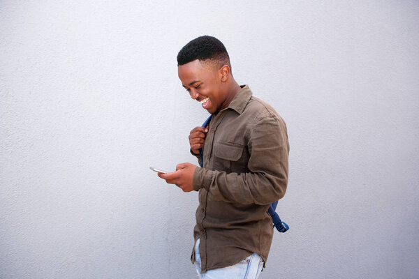 Side portrait of happy young black man looking at cellphone