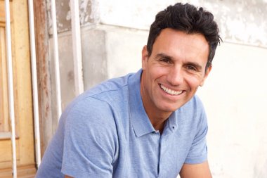 oturma ve kameraya gülümseyen yakışıklı adam