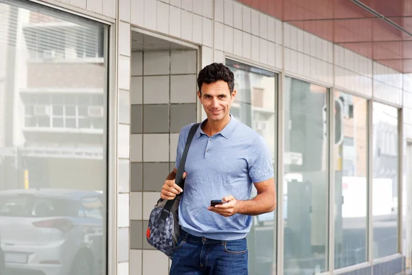 Uomo che cammina in città con borsa e cellulare — Foto Stock