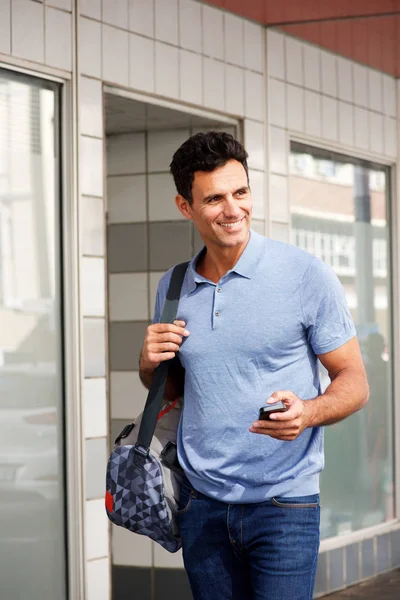 Homme marchant en ville avec sac et téléphone portable — Photo