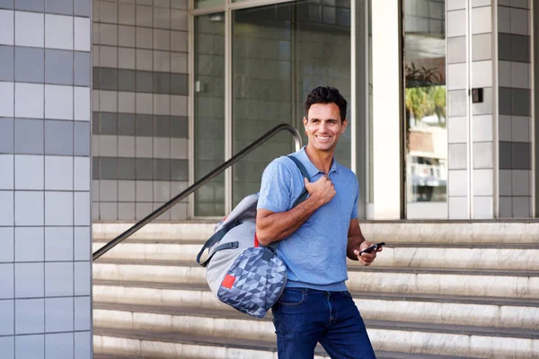 Homme marchant en ville avec téléphone portable et sac — Photo